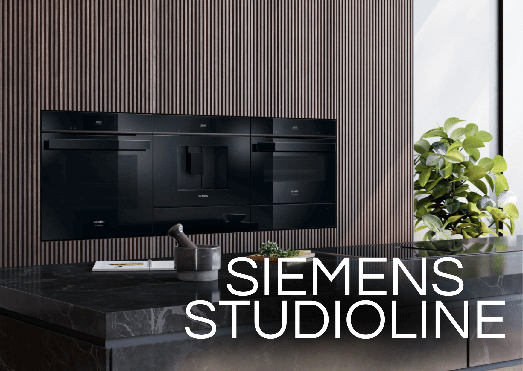 Nahaufnahme einer luxuriösen Küchenzeile der „SIEMENS STUDIOLINE“. Drei schwarze High-End-Einbaugeräte – ein Backofen, ein Kaffeevollautomat und ein Dampfgarer – sind nahtlos in eine dunkelbraun vertäfelte Wand integriert.